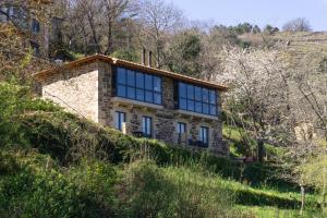 ein Steinhaus mit blauen Fenstern auf einem Hügel in der Unterkunft Ribeira Sacra a Orilla Rio Miño Casas do Pincelo in Pincelo