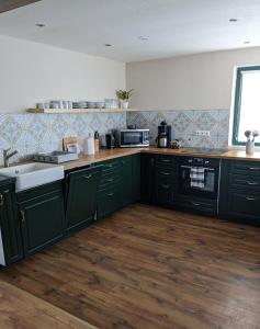 Una cocina con gabinetes verdes y un fregadero. en Große Landhauswohnung, en Ramhusen