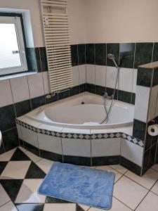Un baño con bañera con ducha y una alfombra azul. en Große Landhauswohnung, en Ramhusen