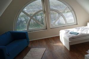 a bedroom with two large windows and a blue chair at Große Landhauswohnung in Ramhusen