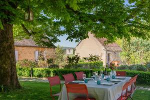 a table with red chairs sitting under a tree at Les Hauts de Saint Vincent B&B proche Sarlat in Saint-Vincent-de-Cosse