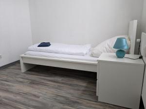 a white bed with a blue lamp on a table at 3 Zimmer Loftwohnung in Itzehoe in Itzehoe