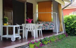 a porch with a chair and a table and some flowers at VILLA Amena WI-FI AC Giardino privato in SantʼAntonio