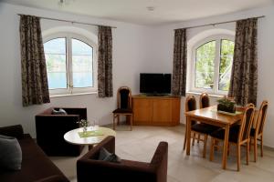 a living room with a couch and a table and two windows at Appartements-Strandschlößl Heitzmann in Seeboden