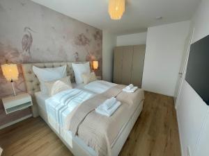 a bedroom with a large white bed with towels on it at Komm & Bleib Nähe Berlin mit Parkplatz in Falkensee