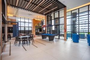 een pooltafel in een kamer met tafels en stoelen bij Studio Completo e Refinado no All Batel - BAT1516 in Curitiba