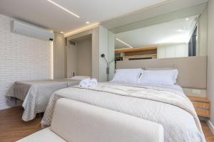 ein Schlafzimmer mit zwei Betten mit weißer Bettwäsche in der Unterkunft Studio no All Batel com Cama Articulada - BAT1805 in Curitiba