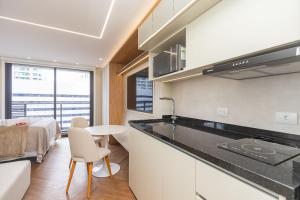 eine Küche mit Theke und Tisch und Bett in der Unterkunft Studio no All Batel com Cama Articulada - BAT1805 in Curitiba