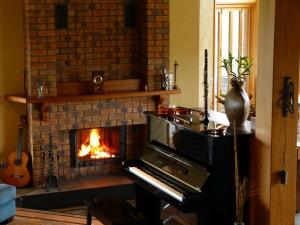 a living room with a fireplace and a piano at Meringa Springs in Halls Gap
