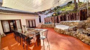a dining room with a glass table and a stone wall at Vila Sitges, big house with pool in Sitges