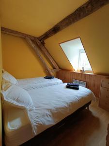 a bedroom with a bed with white sheets and a window at Gîte du Parc Animalier de Boutissaint in Treigny