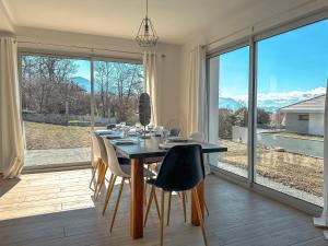 a dining room with a table and chairs and large windows at La Maison les Quatre Saisons - Therme - Ski in Saint-Martin-d'Uriage