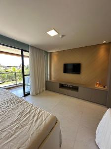 a bedroom with a flat screen tv on a wall at Flats, Apartamentos e Bangalôs na Praia dos Carneiros, ao lado da Igrejinha de São Benedito in Praia dos Carneiros