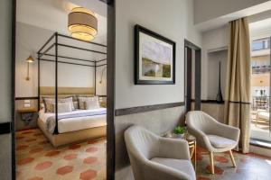 Una habitación de hotel con una cama y dos sillas. en Flâneur Suites Corso, en Roma