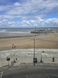 a beach with people walking on the sand and the ocean at Imperial Apartment sea view Margate in Margate