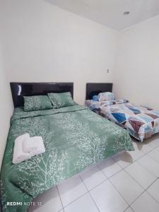 1 dormitorio con 2 camas y edredón verde en Kos Menteng Jakpus, en Yakarta
