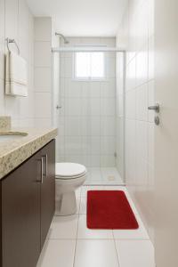 a bathroom with a toilet and a red rug at Apartamentos Verano in Natal