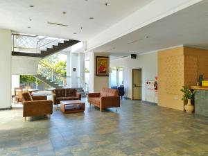 a living room with couches and chairs and a staircase at Apartment Skyland Jatinangor by Mustika in Cikeruh
