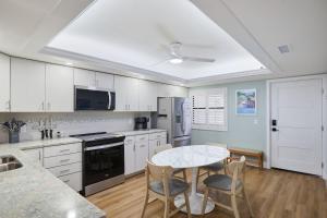 a kitchen with white cabinets and a table with chairs at Pointe Santo C6 - Upgraded Walk Out Residence at Pointe Santo in Sanibel