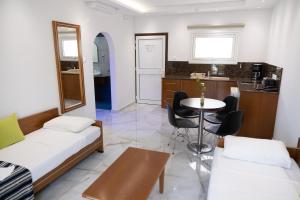 a room with two beds and a table and a kitchen at Loutsiana Deluxe Apts in Ayia Napa