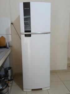 einen weißen Kühlschrank mit einer Mikrowelle darüber in der Unterkunft Casas de pequeno porte ocian praia grande sp in Samaritá