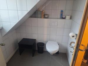 ein kleines Badezimmer mit Toilette und Hocker in der Unterkunft WOB Hotel in Wolfsburg