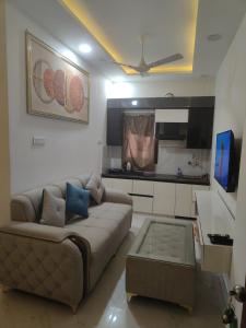 a living room with a couch and a kitchen at Iconic Royal Studio Apartment Near Expo Mart in CHI 5 in Greater Noida