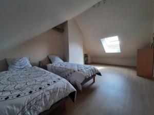 a attic bedroom with two beds and a window at Maison Chez Polo in Étivey