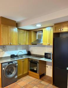 a kitchen with wooden cabinets and a washer and a dishwasher at Exclusive apartment with a terrace in Mora de Rubielos