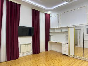 タシュケントにあるLaurel Hotelのリビングルーム(赤いカーテン、薄型テレビ付)