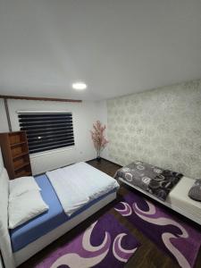 a bedroom with two beds and a purple rug at Apartman Vany in Tuzla