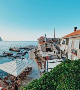a beach with tables and umbrellas next to the water at Apartments First Line in Petrovac na Moru