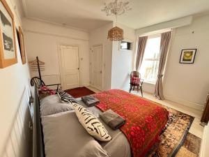 a bedroom with a bed with a red blanket at Augusta garden apartment in Sheringham