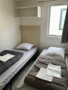 two beds in a room with a window at camping les dunes 5 étoiles mobil home 6 personnes A16 in Torreilles +19 photos