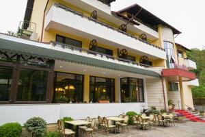 a restaurant with tables and chairs in front of a building at Pensiunea Iulia Star in Băile Olăneşti