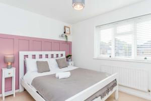 a bedroom with a white bed with a pink headboard at Modern 3 Bedroom Home in Swindon with Parking in Swindon
