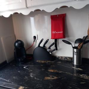 a kitchen counter with utensils and a red bag on the wall at Alojamento cosy in Fuzeta