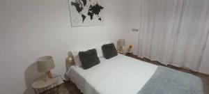a white bedroom with a bed with two pillows on it at Alojamento cosy in Fuzeta