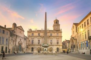 a building with a clock tower and a fountain in front at Numéro Quarante Arles Center in Arles