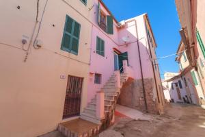 ein rosa Gebäude mit Treppen in einer Gasse in der Unterkunft Nel cuore di Rio Marina in Rio Marina