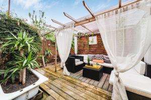 a backyard deck with a pergola and a couch at Relax 2BDR with Sauna, Hot Tub and Cinema in London