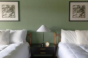 a bedroom with two beds and a table with a lamp at The Ellison Inn & Lounge in Ellison Bay