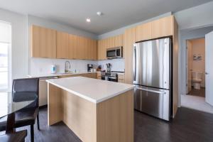 una cucina con frigorifero in acciaio inox e mobili in legno di Luxury Private Apt with Pool a White Plains