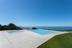 a large swimming pool on a patio with the ocean in the background at Sunset Horizon - BY SCH in Pederneira