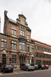 an old brick building with cars parked in front of it at B&B Suites FEEK in Antwerp