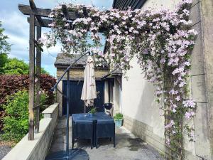 a pergola with a table and flowers on it at Chez Mona in Florenville