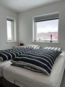 zwei Betten in einem weißen Zimmer mit Fenster in der Unterkunft Private home with sea view in Ilulissat