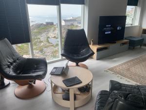 ein Wohnzimmer mit 2 Stühlen und einem Tisch mit einem Laptop in der Unterkunft Private home with sea view in Ilulissat