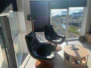 2 Stühle und ein Tisch in einem Zimmer mit Aussicht in der Unterkunft Private home with sea view in Ilulissat