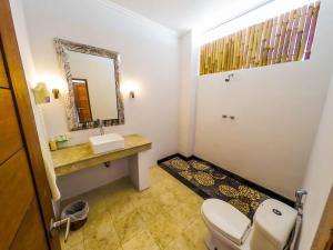 a bathroom with a toilet and a sink and a mirror at Ecosfera Hotel & Spa in Canggu